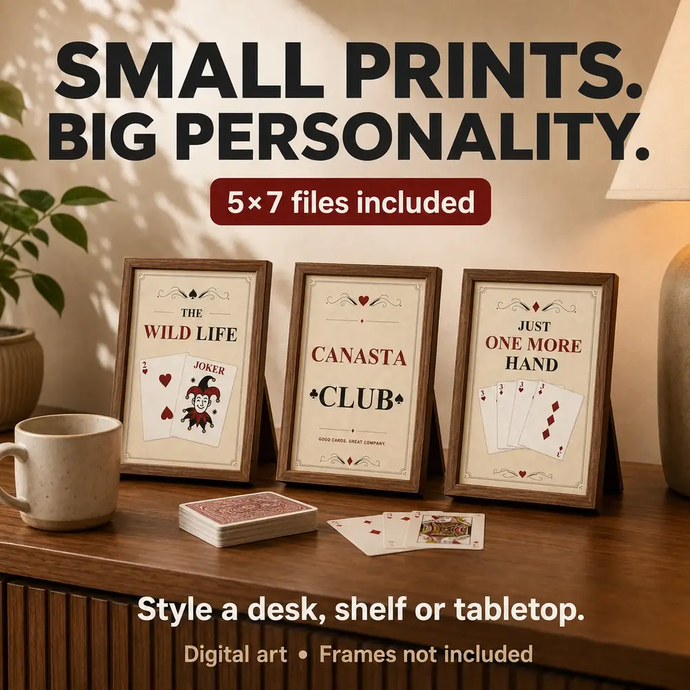 Three small vintage Canasta prints in standing wooden frames on a tabletop beside a mug and playing cards